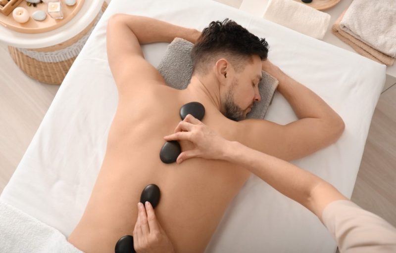 Handsome man having stone massage in spa salon